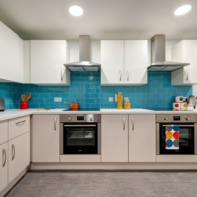 Kitchen interior with white cupboards and teal coloured tiles