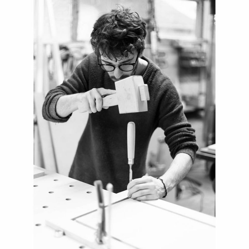 Falmouth University graduate, Dan Bethell using a hammer and chisel to make furniture