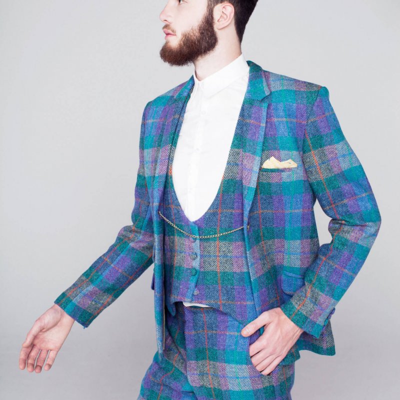 Model in tweed three piece suit in bright blues, purples and greens.