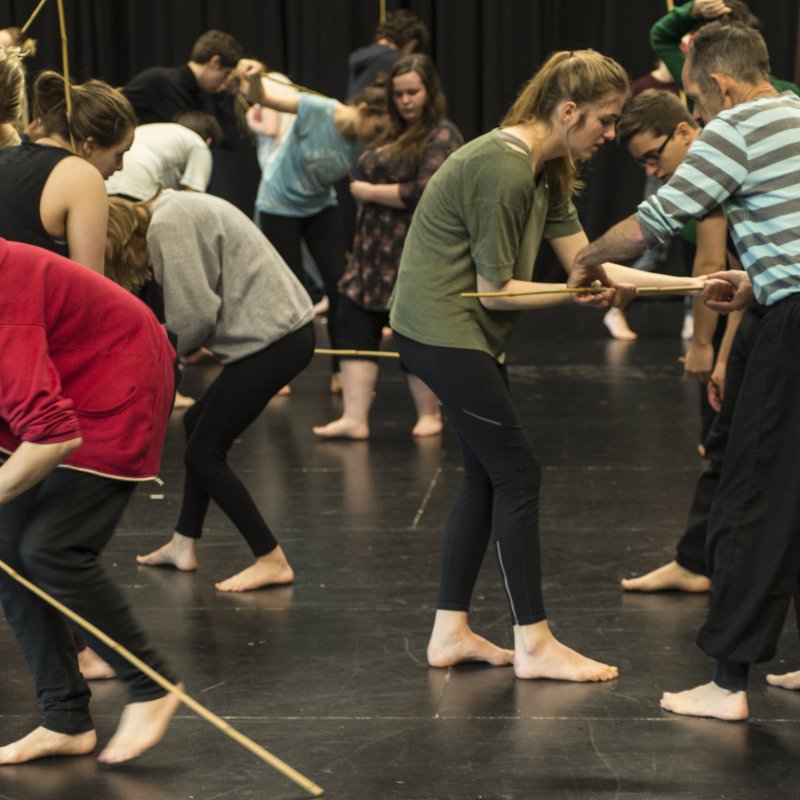 Students in workshop interacting between each other and bamboo sticks.