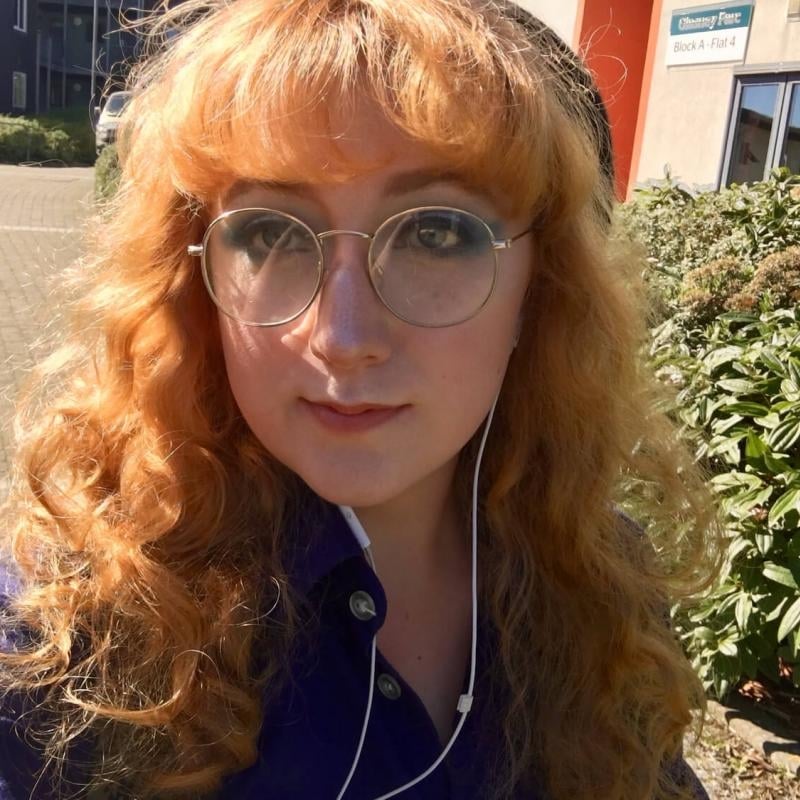 Falmouth University student wearing white headphones and a purple shirt