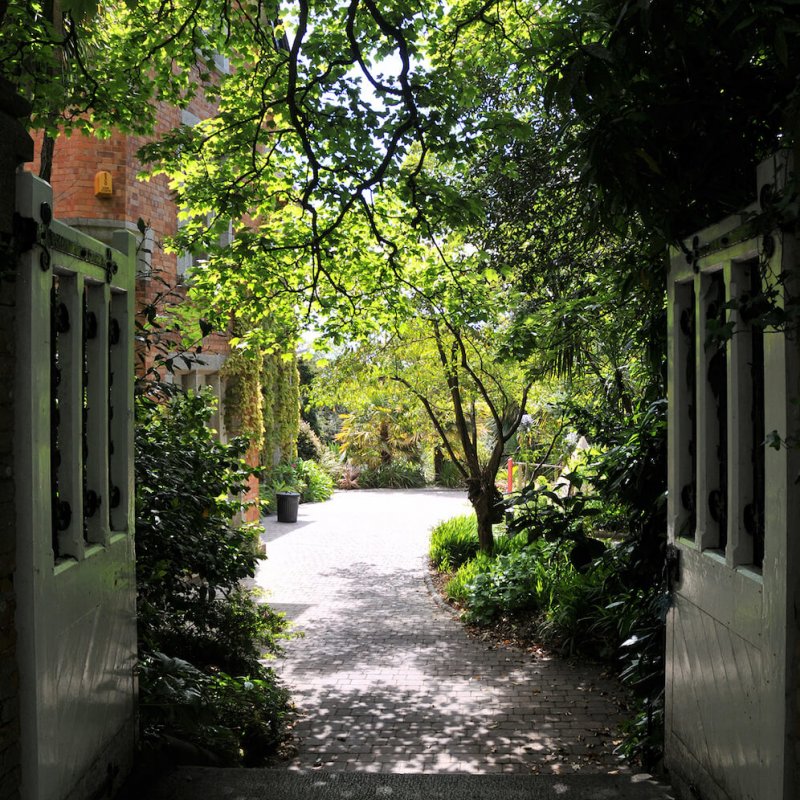 Through the wooden gates looking into the gardens at Falmouth campus.