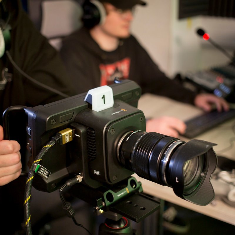 A Falmouth University student operating a camera with a student in the background