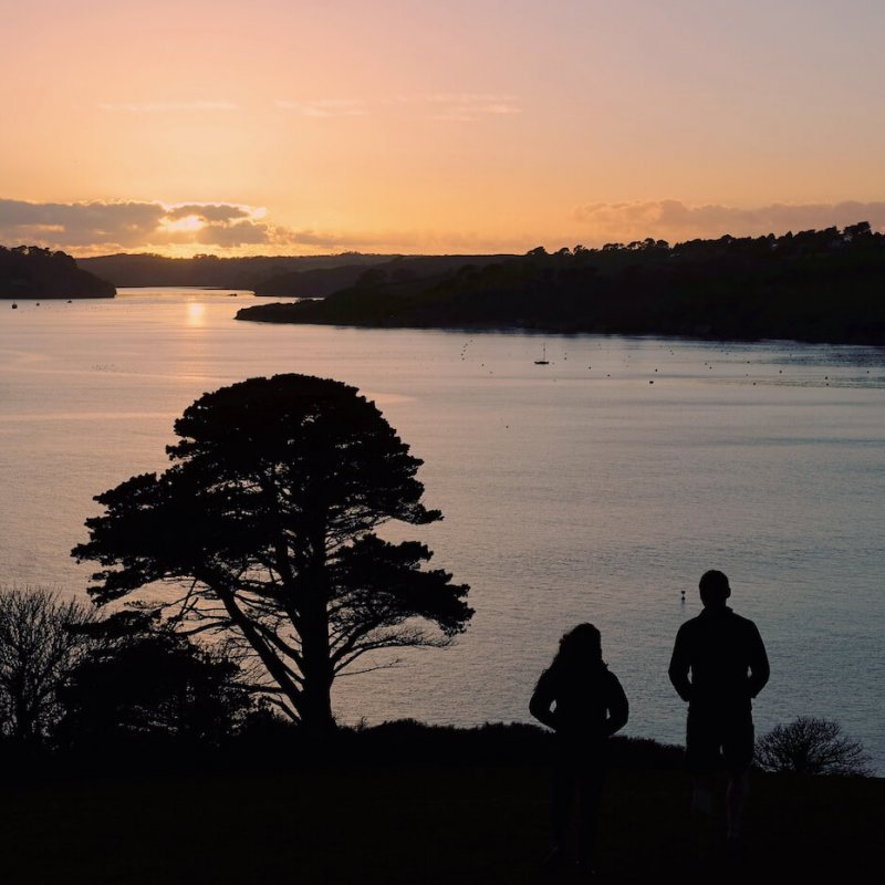 Silhouettes of students looking over the Fal estuary at sunset.