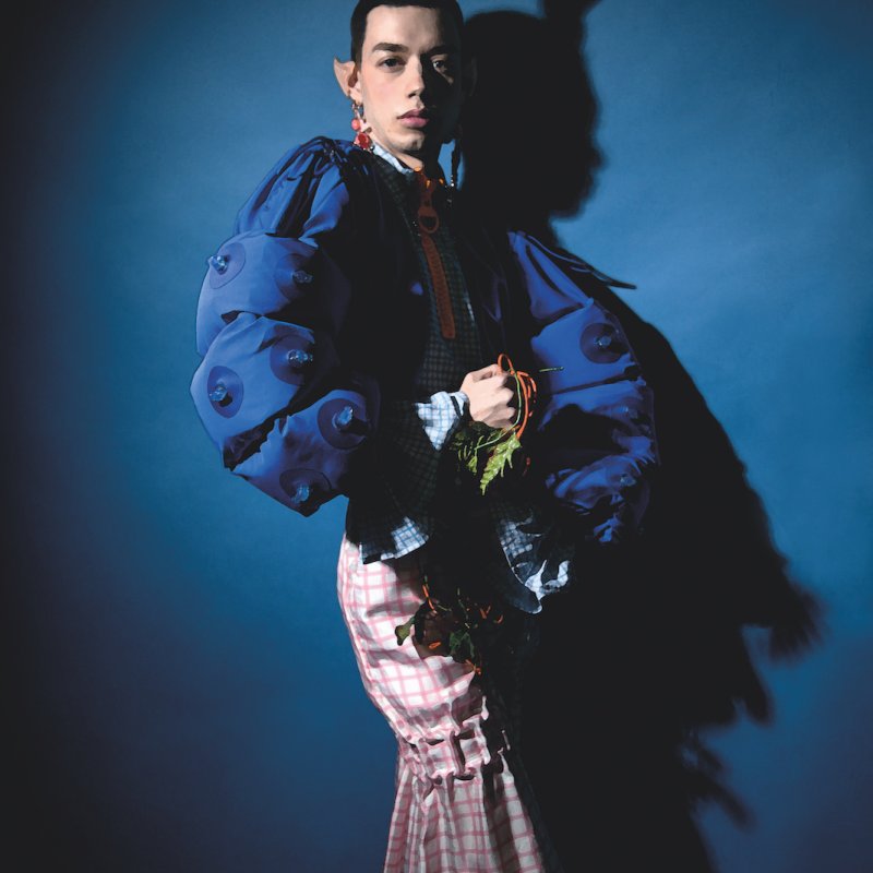 Model wearing flamboyant blue jacket and stingray headpiece.