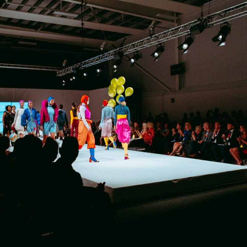 Catwalk show, model carrying yellow balloons