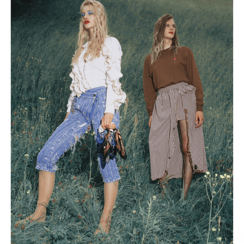 Two female fashion models in a field, wearing Jeans and a skirt