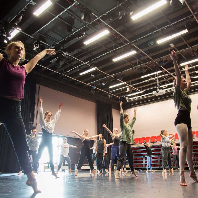 Falmouth University dance students raising their arms in a dance studio