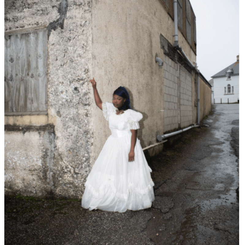 A woman in a white dress posing on a street