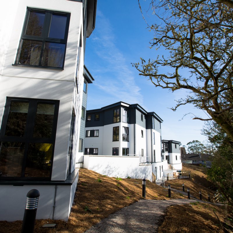 Packsaddle Hill Exterior – angular white and slate buildings along tree-lined and lit pathway