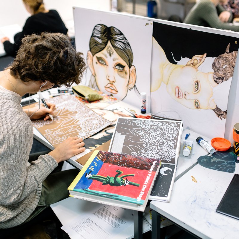 Male student drawing at a desk