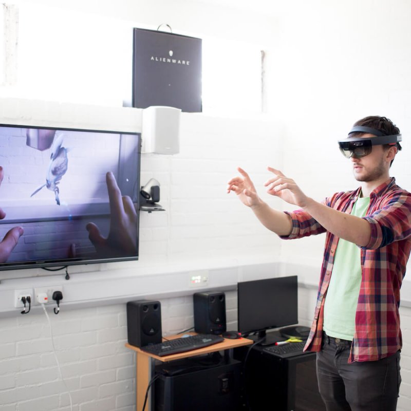 A Falmouth University student wearing a VR headset with a flat screen TV