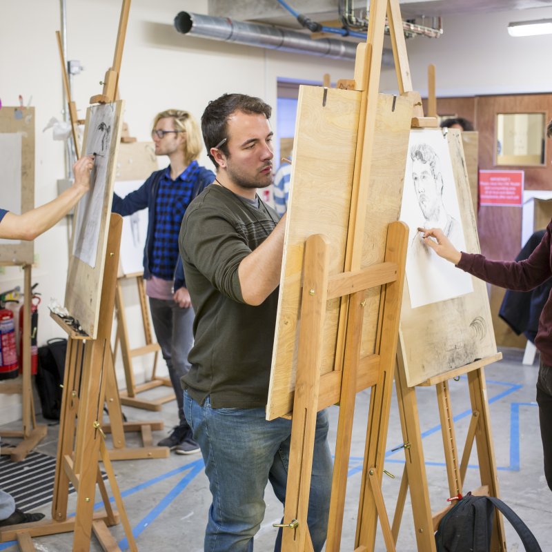 four male students at easels in a life drawing class