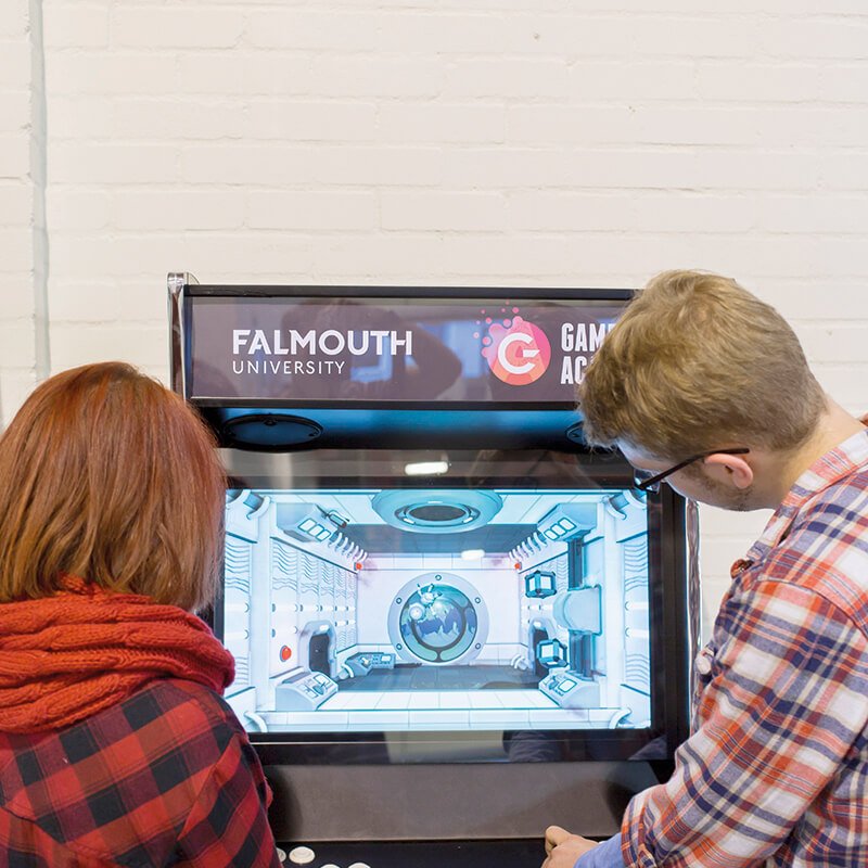 Two Falmouth University students playing on a retro games machine