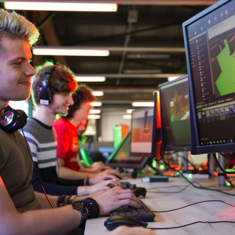 Games student smiling and working on artwork on a computer screen.