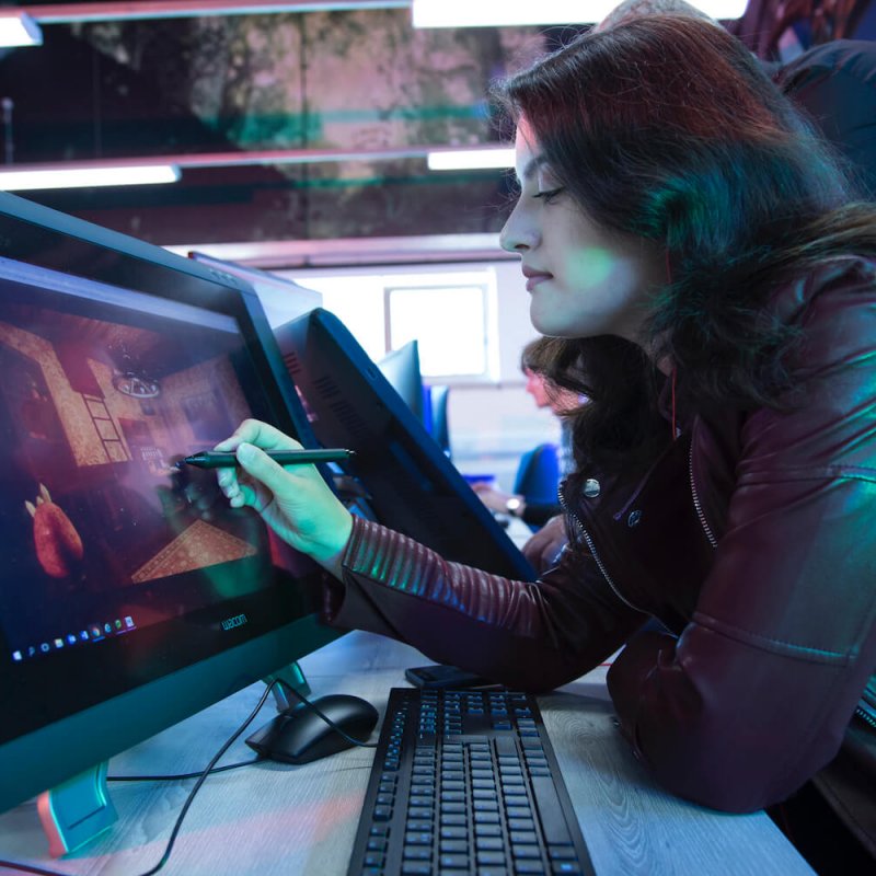 Games academy female student in black leather jacket drawing at graphic tablet