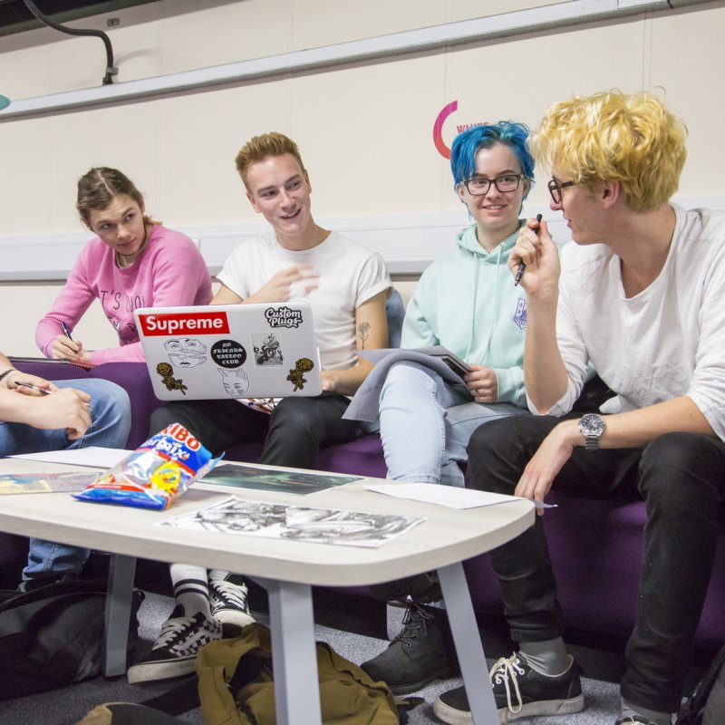 Games students on sofas smiling and looking at laptop.