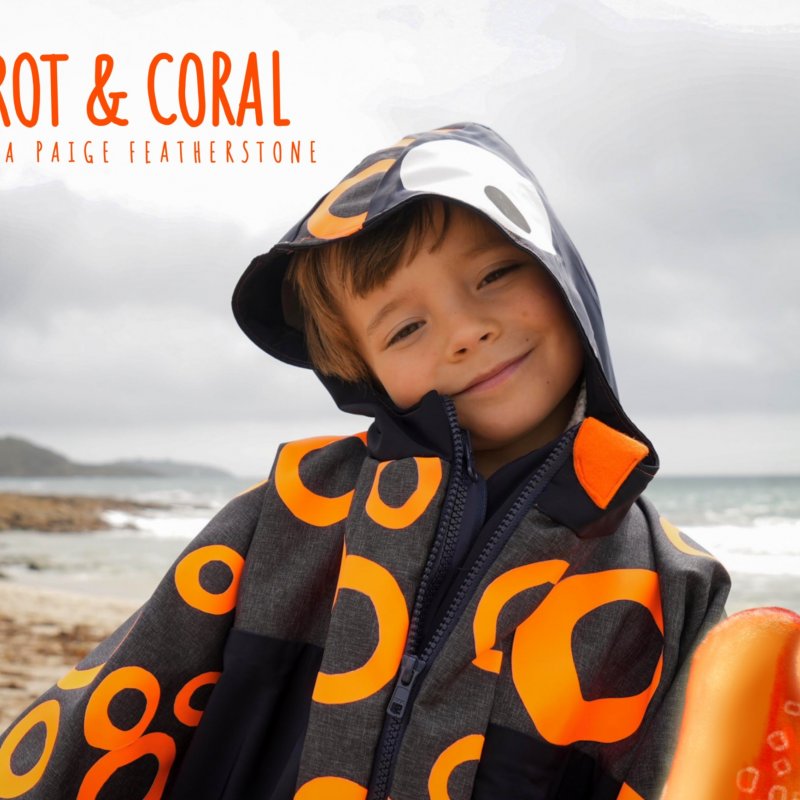 A young boy wearing a hooded jacket on the beach