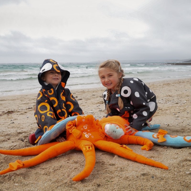 Two young children on the beach with a star fish toy