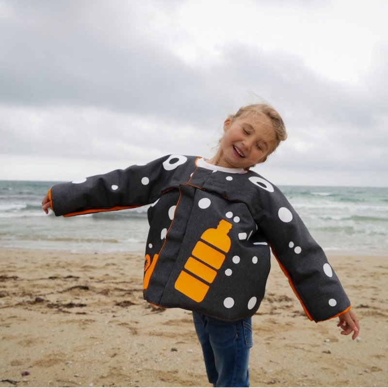 A young girl on the beach, wearing a jacket