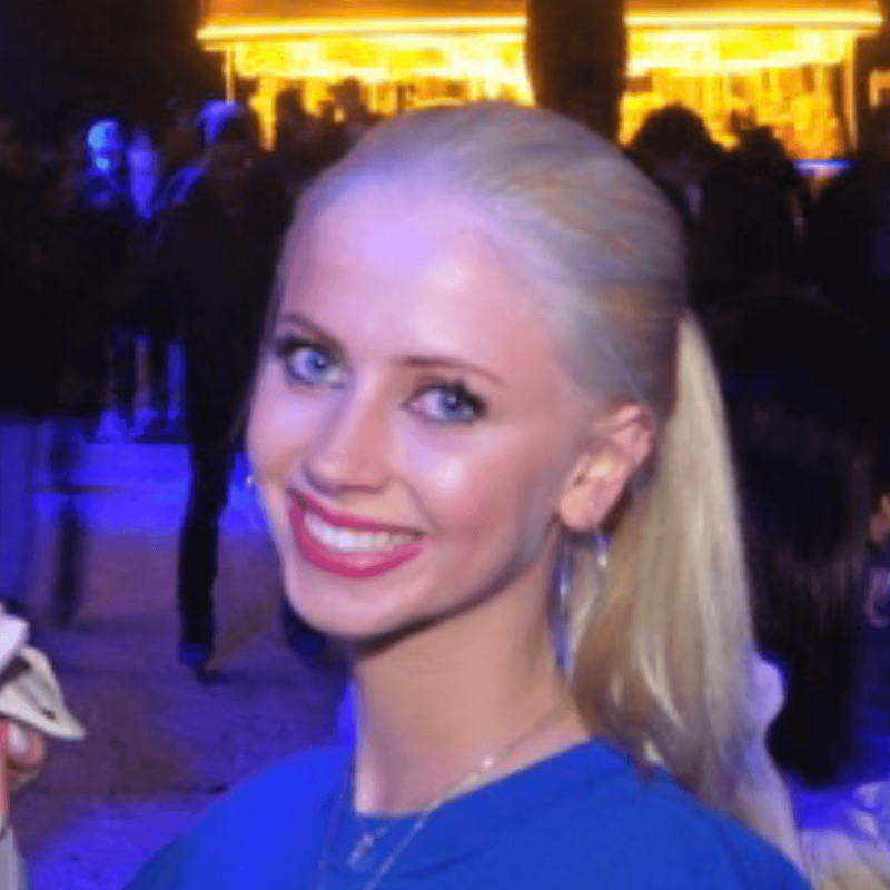 A girl with blonde hair smiling, wearing a blue jumper