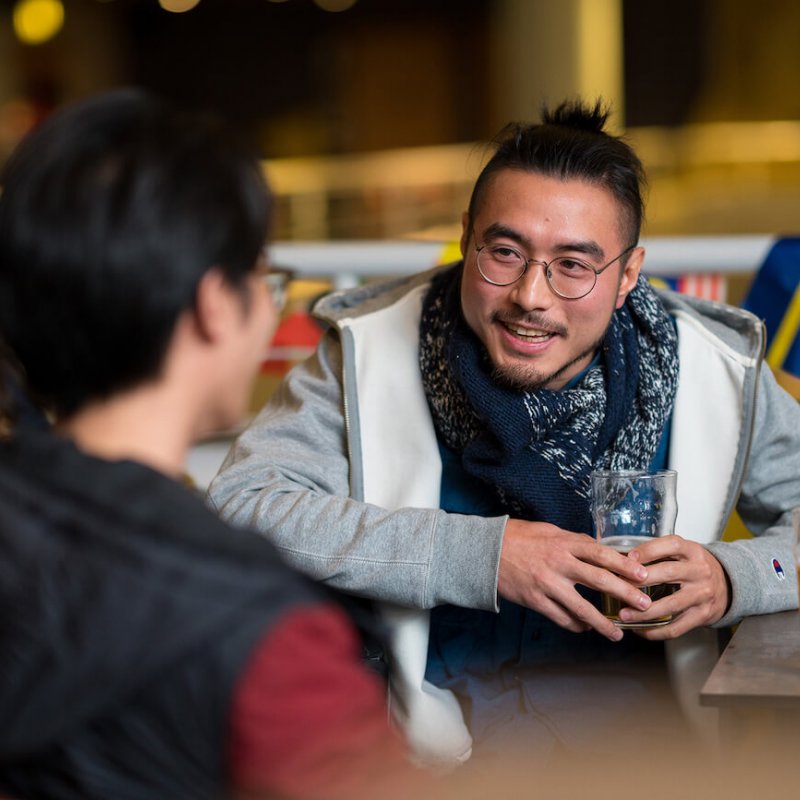 Students chatting to each other with a beer in hand.