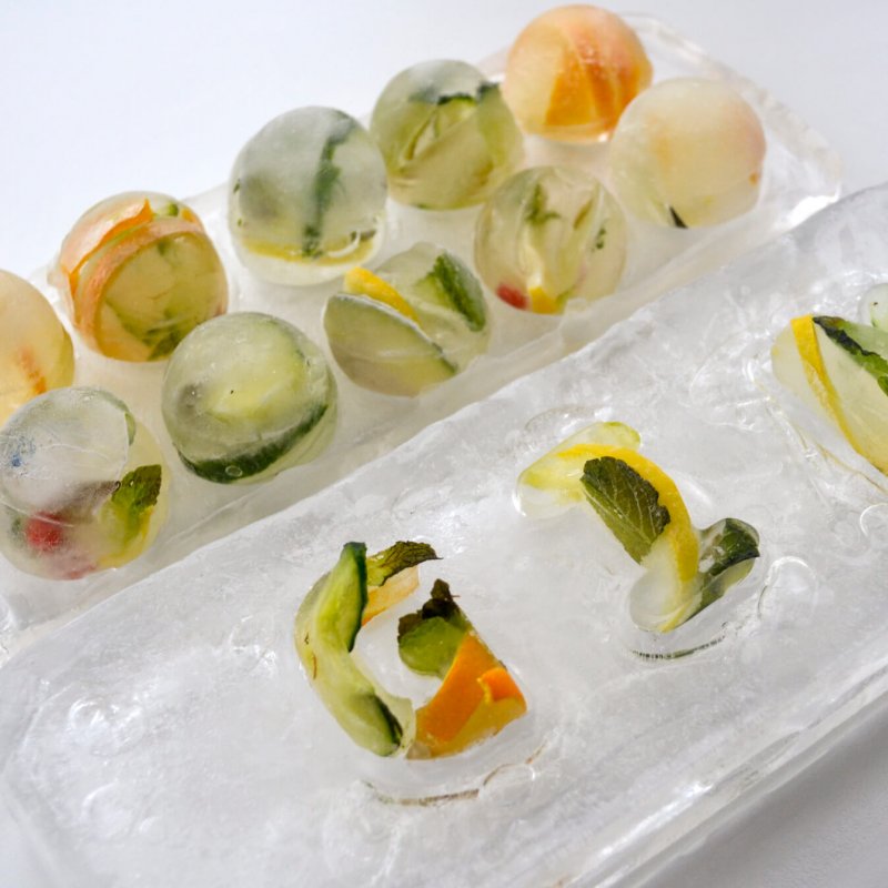 Ball shaped ice cubes with citrus fruits frozen within them.