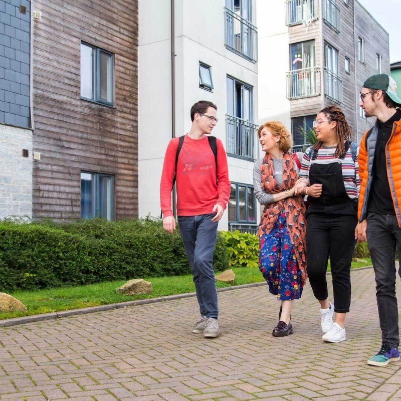 Students walking through Glasney Village with arms linked.