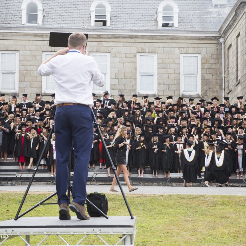 View of photographer taking group photograph of 2019 graduates in gowns and hats