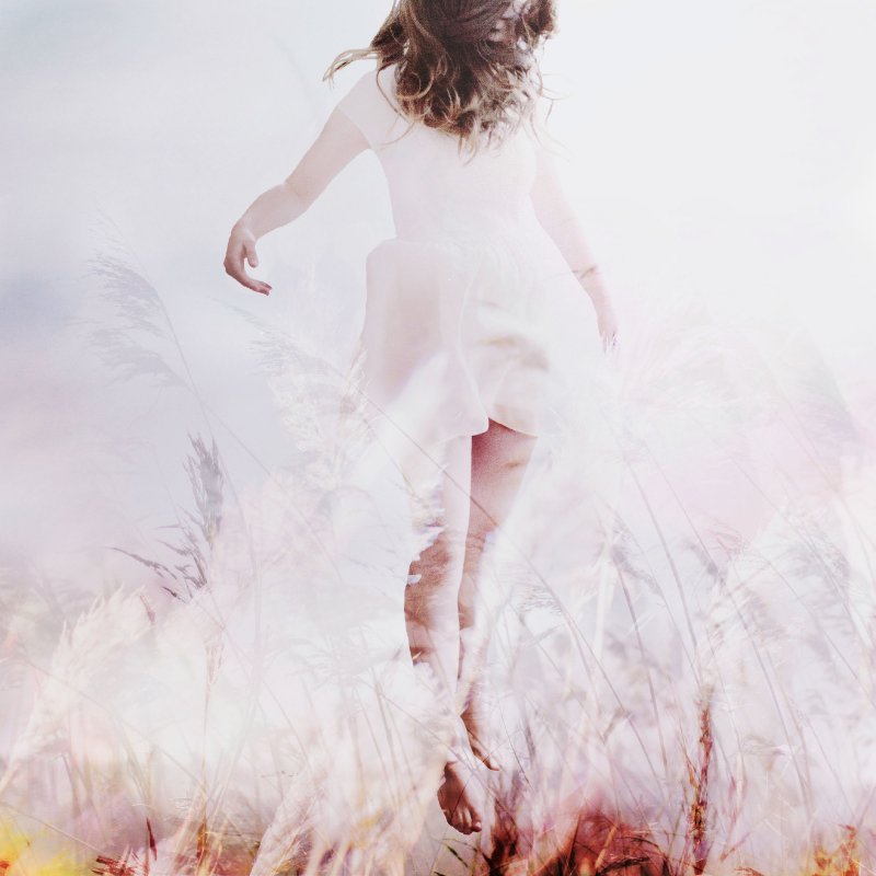 Girl in white dress floating through a field of corn.
