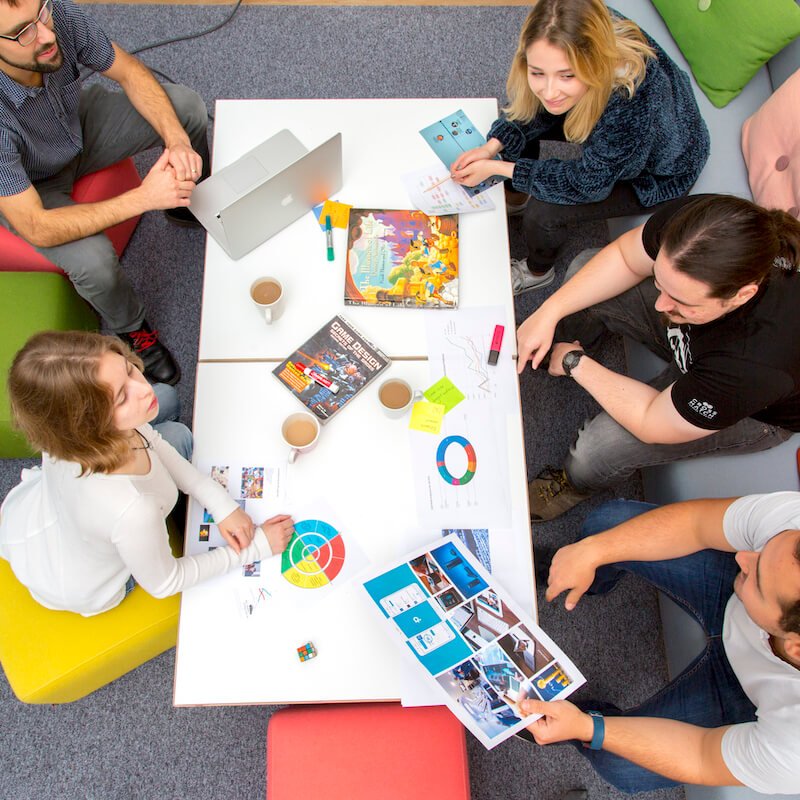 Falmouth University students sitting on brightly coloured cushions and chatting.