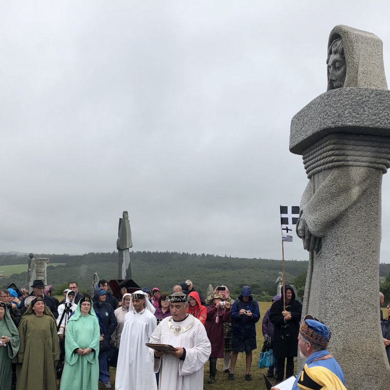 Group of people in religious costumes stood around statue