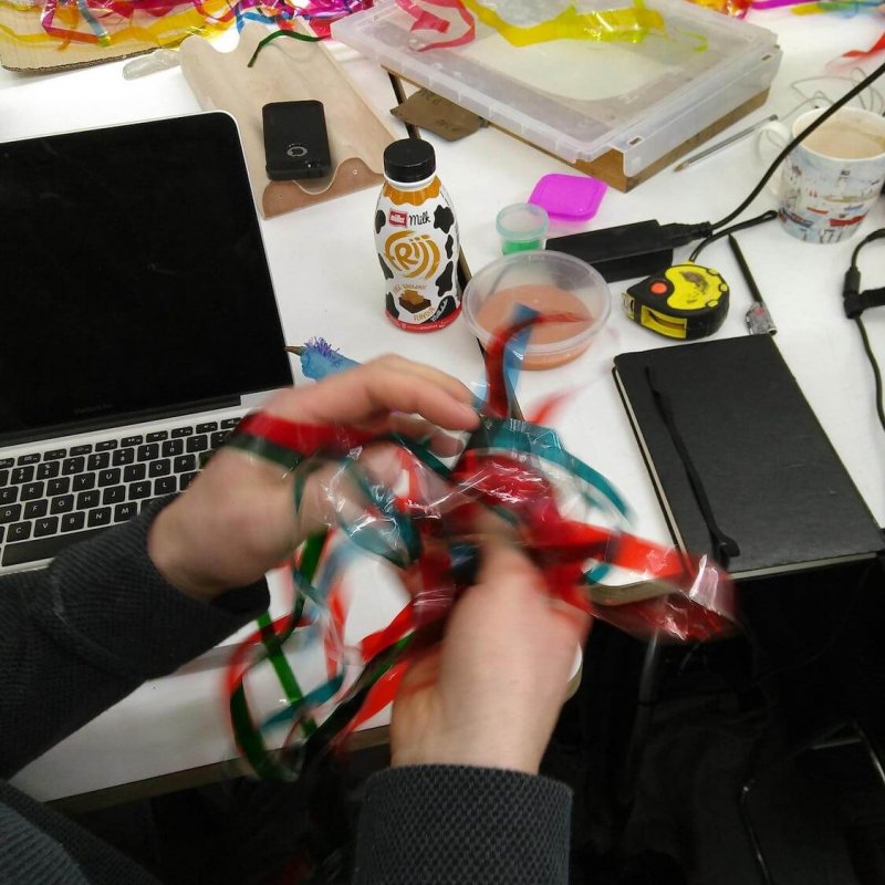 Hands playing with red and green sensory string on a messy desk