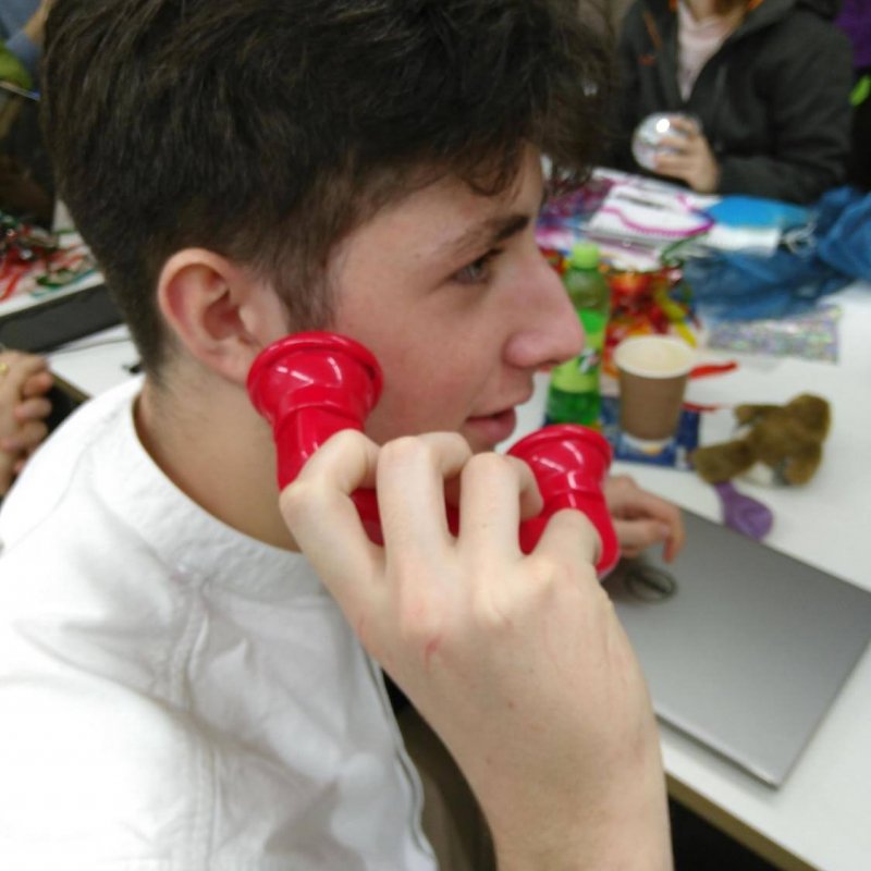 A man with dark hair holding a red sensory object