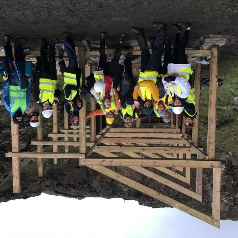 Students in high vis jackets under wooden structure