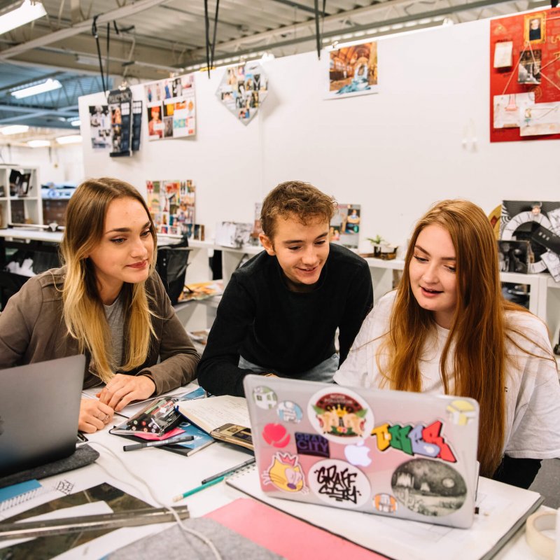 Students looking at a laptop together in design studio at Falmouth University