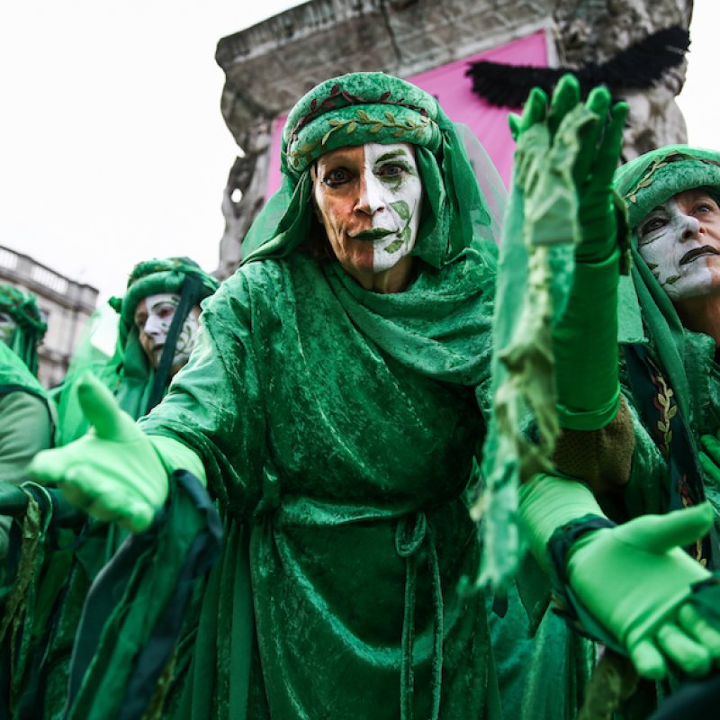 A crowd of people dressed in green robes with their faces painted
