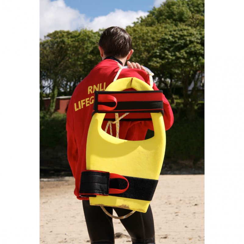 RNLI lifeguard carrying yellow float on back