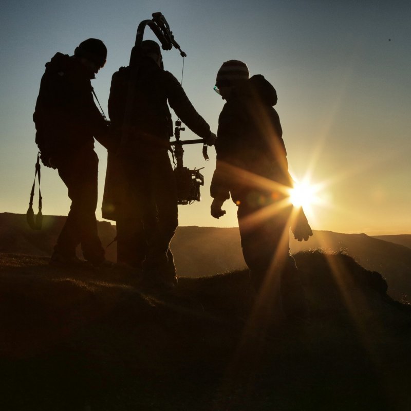 Silhouettes of film crew with sun setting in background