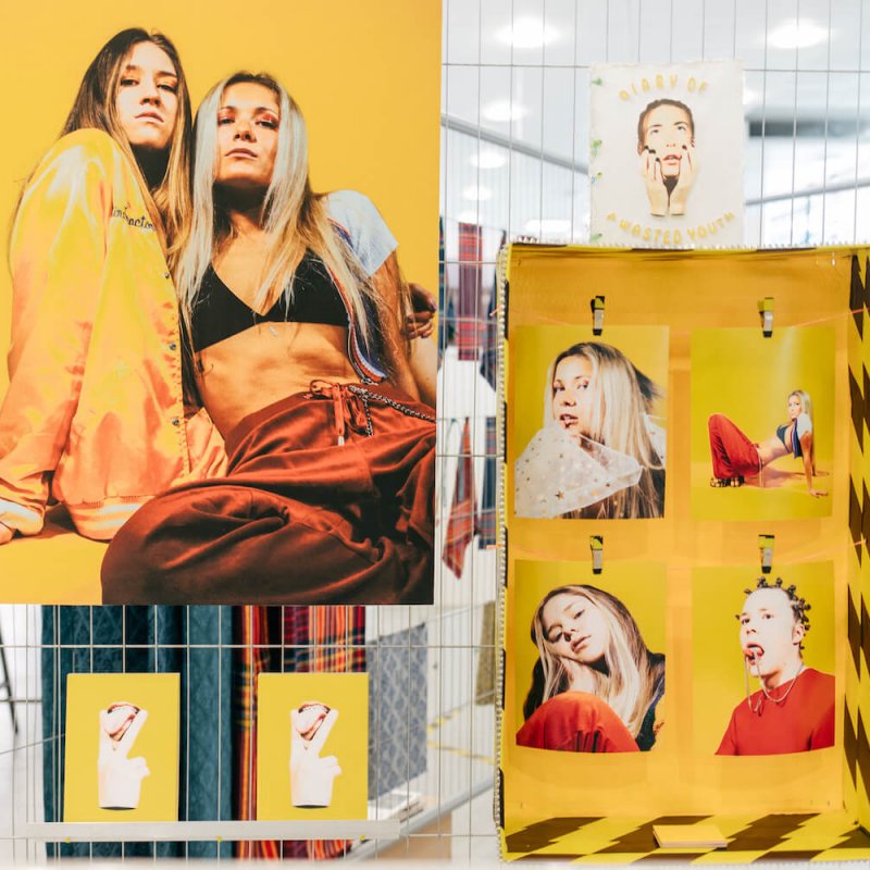 Exhibition of fashion photography featuring models on yellow background.