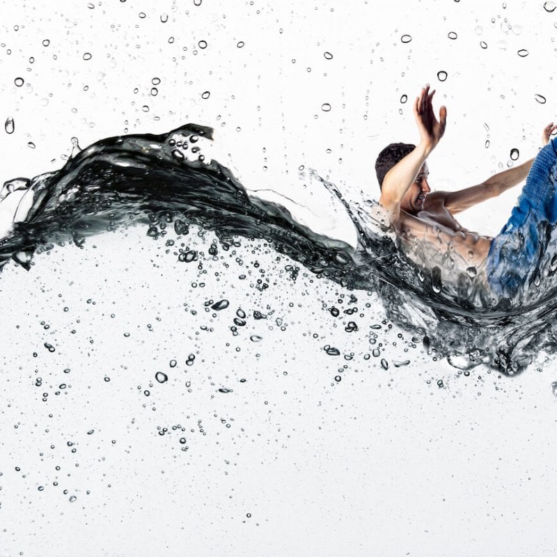 A man wearing jeans, falling through dark water