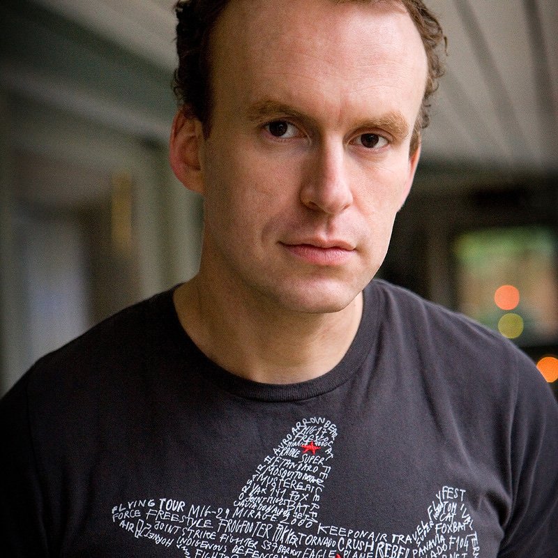 Portrait of writer, Matt Haig, with an aeroplane made of words on his t-shirt.