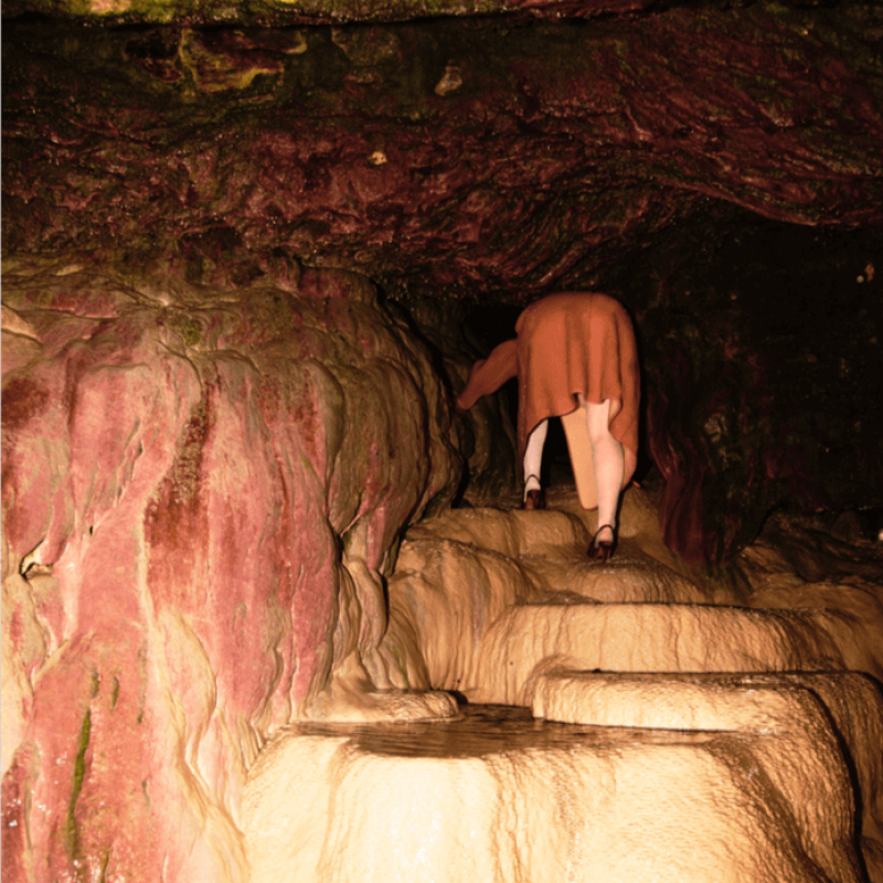 A person climbing through a cave