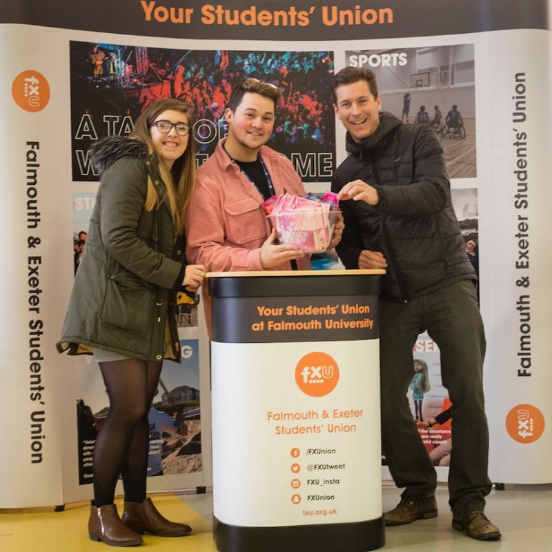 Students from Falmouth's student union posing at their stand at an event.