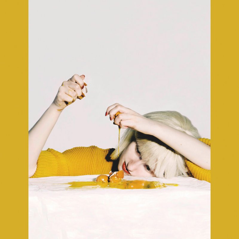 Girl with head on table breaking eggs in front of her.