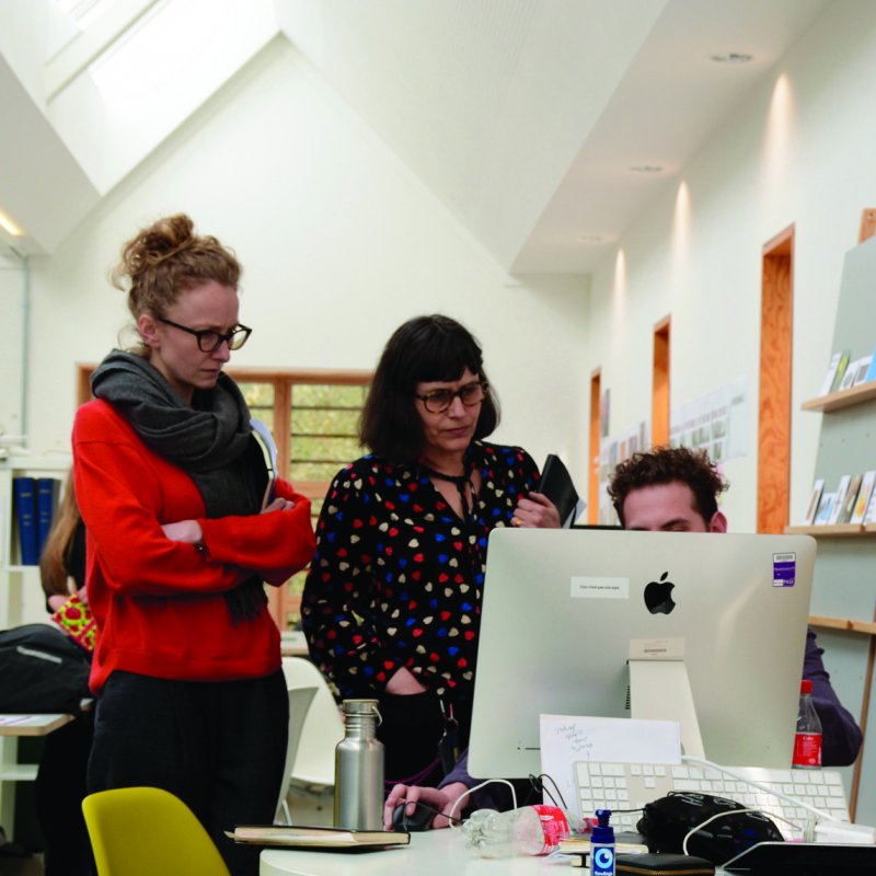 Two women standing looking at an iMac