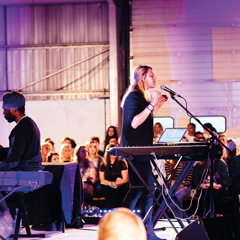 Falmouth University music students on stage singing and playing keyboard.