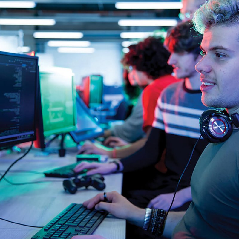 A student coding at a computer, wearing headphones