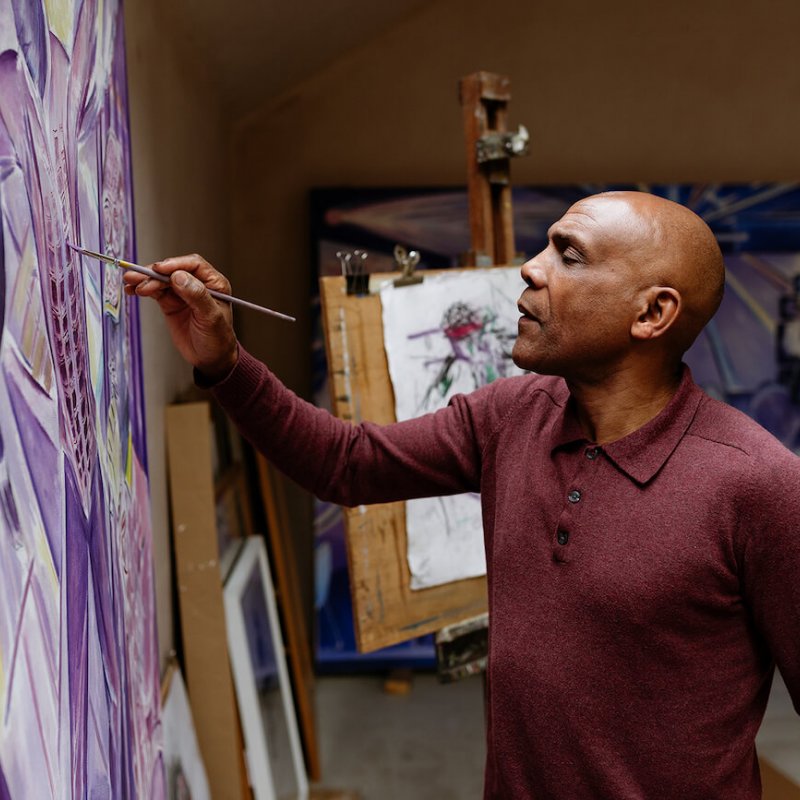 Denzil Forrester painting on a canvas in his studio