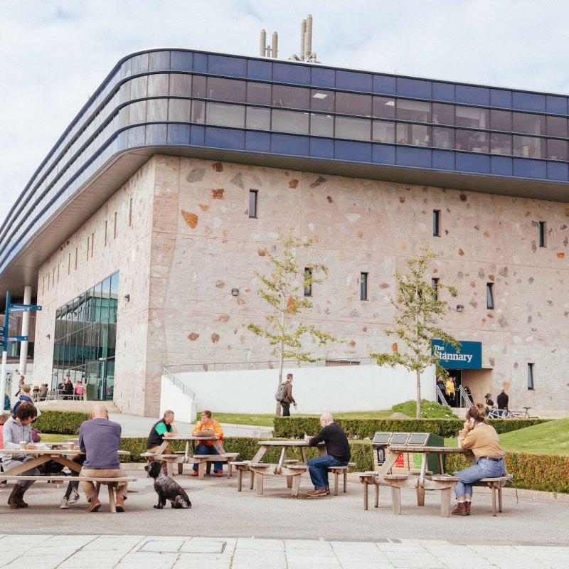 People and benches outside the Stannary buidling on Penryn campus.